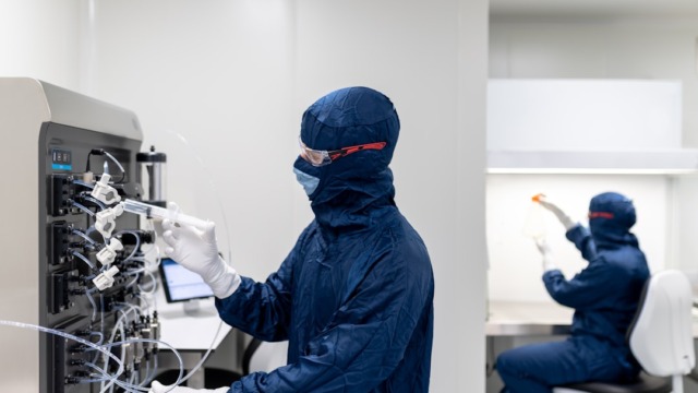 Laboratory technicians working in the lab | a few people in protective gear working on a computer