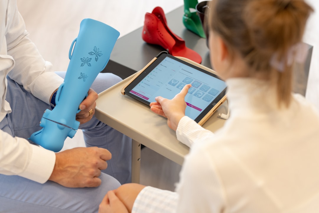 Orthopedic specialists engage in an interactive adjustment session, utilizing digital tools to refine the functionality of an orthotic device. | a woman sitting on a table using a tablet