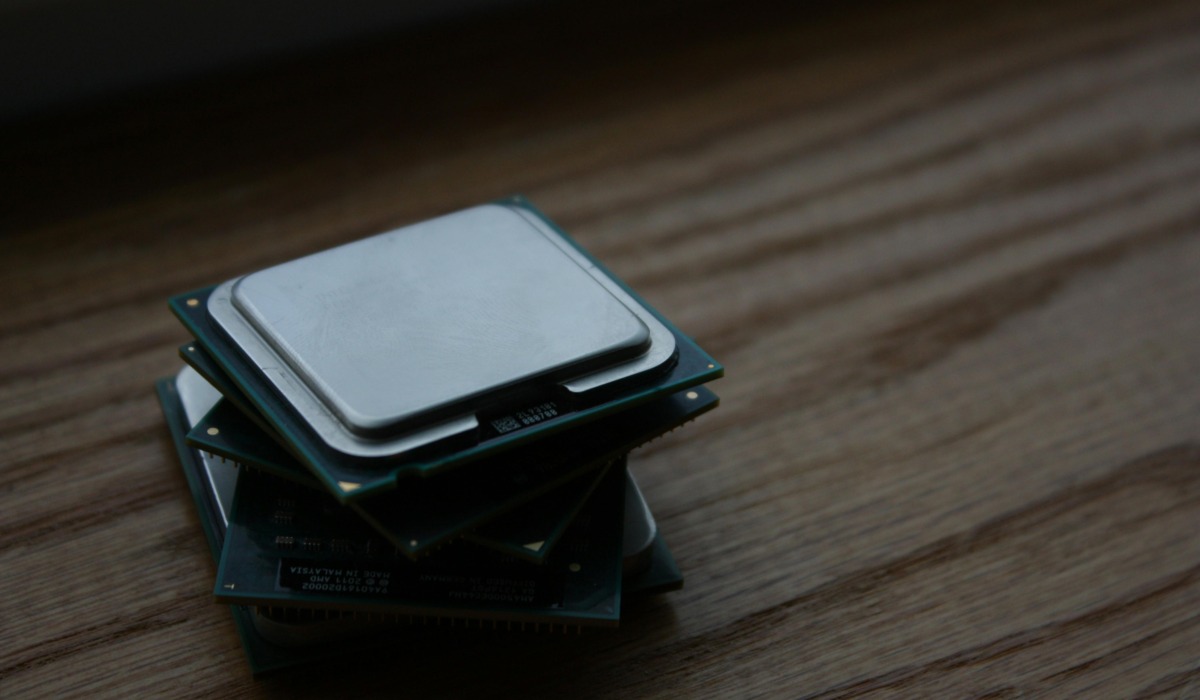 Close-up of multiple computer CPUs stacked on a wooden surface, showcasing technology components.