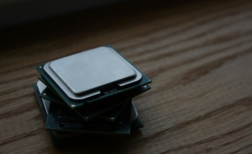 Close-up of multiple computer CPUs stacked on a wooden surface, showcasing technology components.