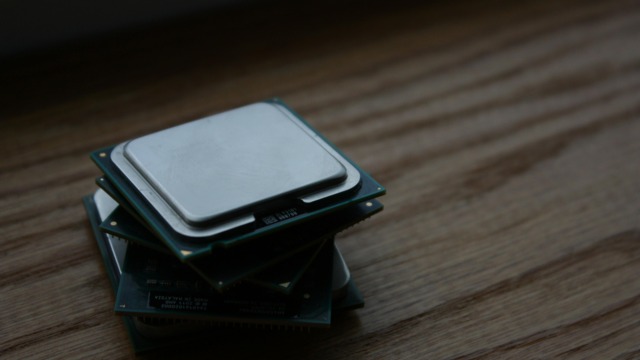 Close-up of multiple computer CPUs stacked on a wooden surface, showcasing technology components.