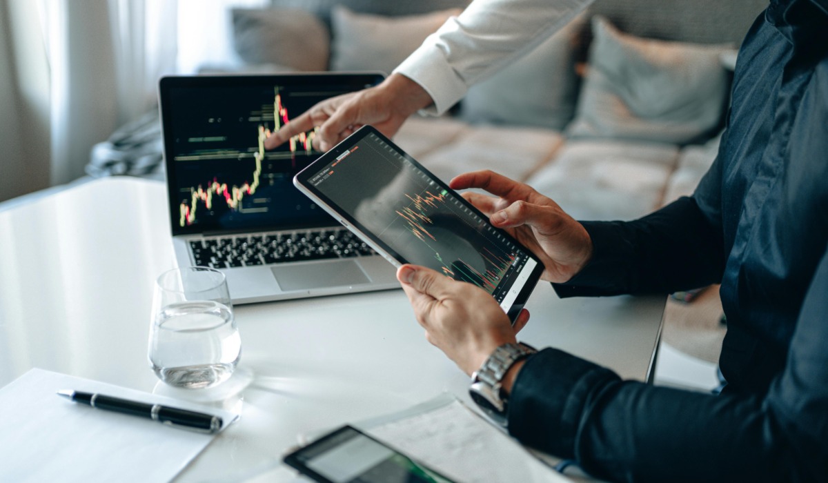Business professionals analyzing financial data on digital devices in office setting.