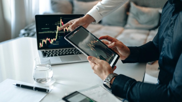 Business professionals analyzing financial data on digital devices in office setting.
