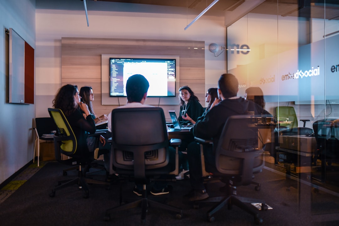 Startup team @ EmbedSocial office | a group of people sitting in chairs in front of a projector screen