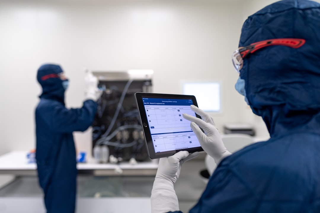 Laboratory personnel working with electronic batch record software | a few people in blue lab coats looking at a computer screen