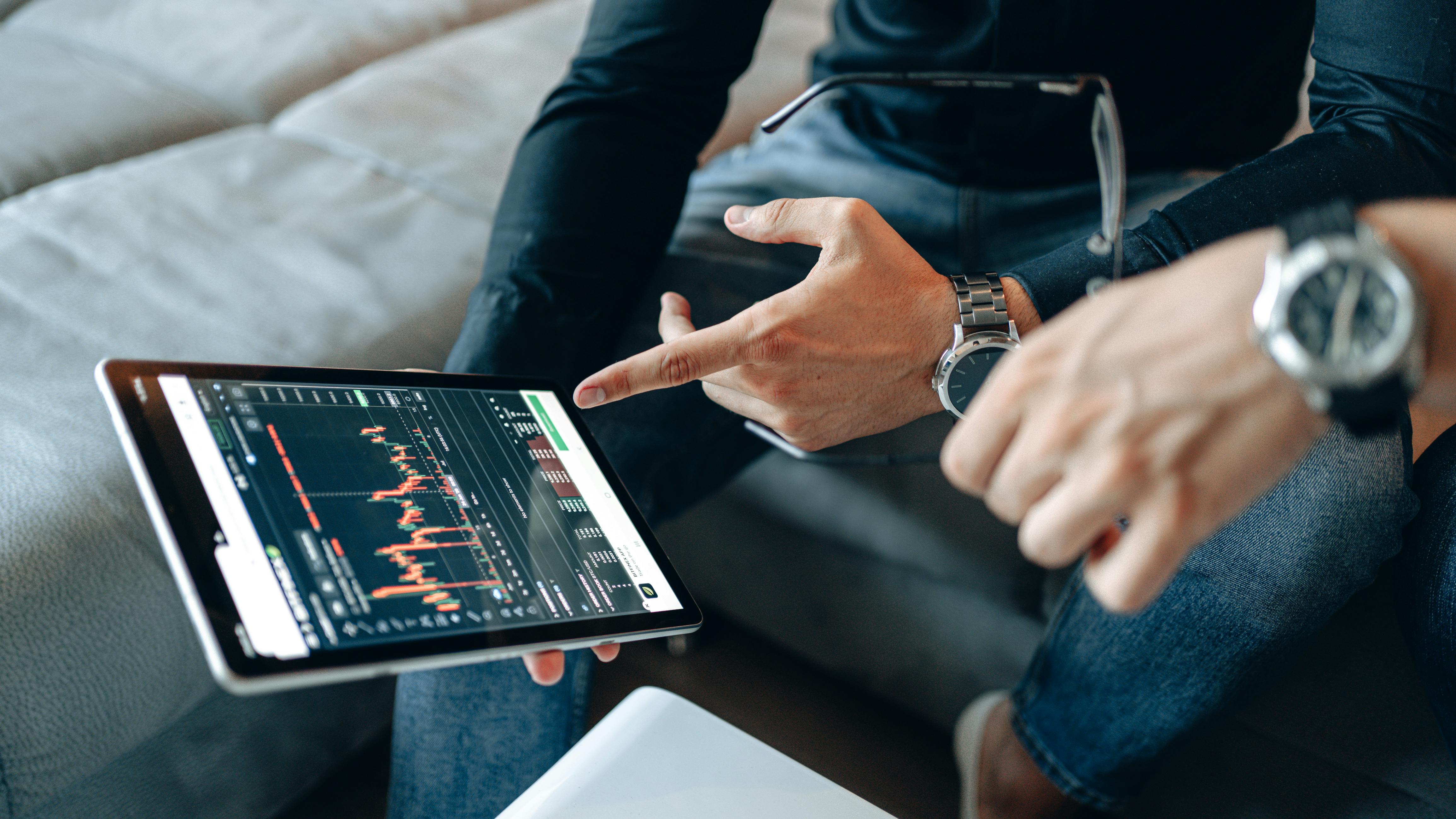 Two people discussing cryptocurrency data on a digital tablet.