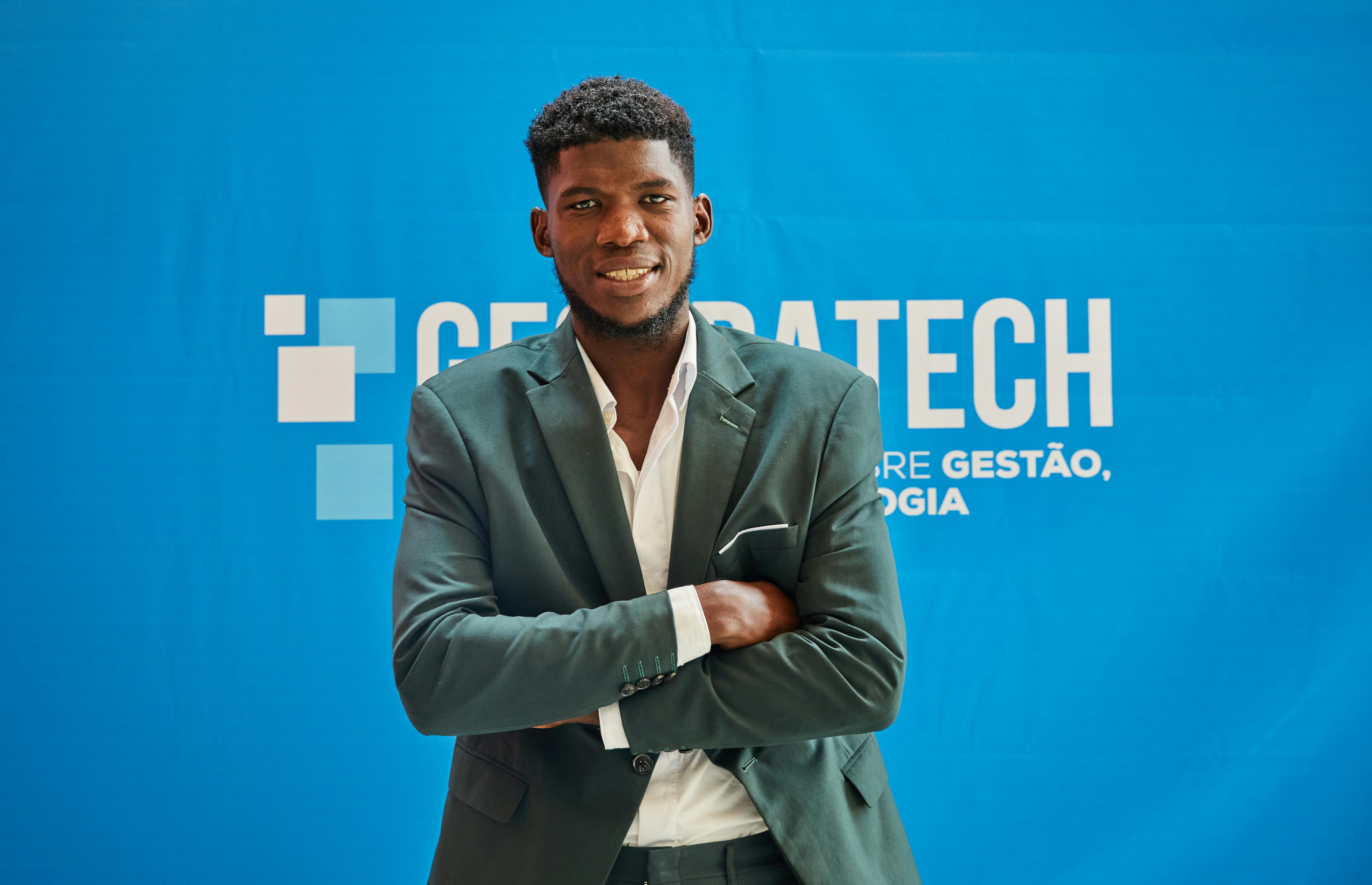 Businessman in suit smiling confidently with arms crossed at a technology event.
