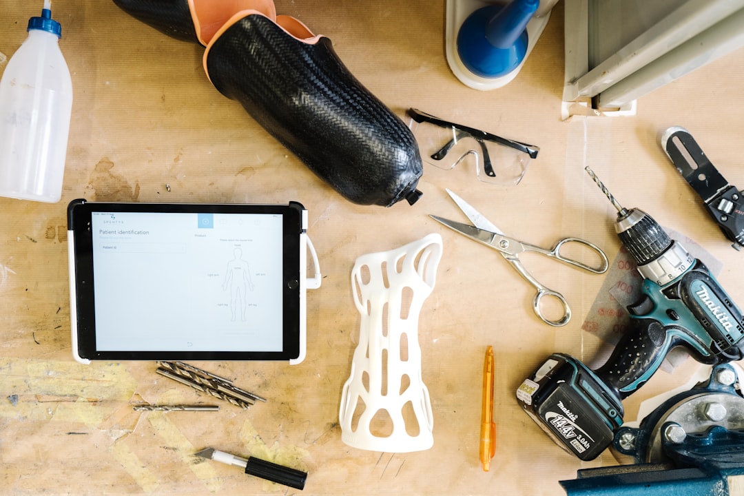 Custom made orthoses designed digitally and created with a 3D printer in an orthopedic technician workshop | white and black scissors beside white plastic hair comb and black leather pouch